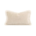 A rectangular lumbar throw pillow in cream with a raised geometric Greek key pattern and fringed edges, shown on a solid white background.